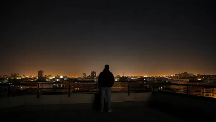 Persona che osserva il cielo notturno arancione sopra una città illuminata