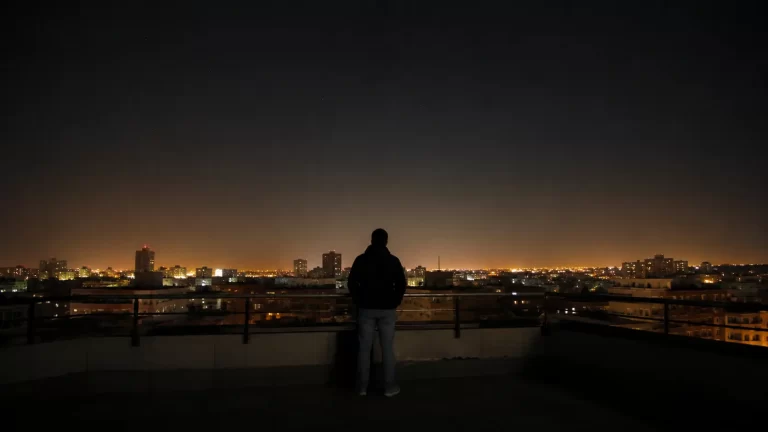 Persona che osserva il cielo notturno arancione sopra una città illuminata