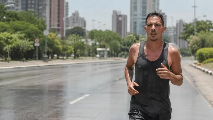 Persona che corre lungo un viale assolato in città in una giornata estiva ad alto livello di ozono